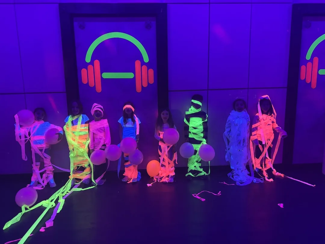 Kids playing a glowing party game under black lights