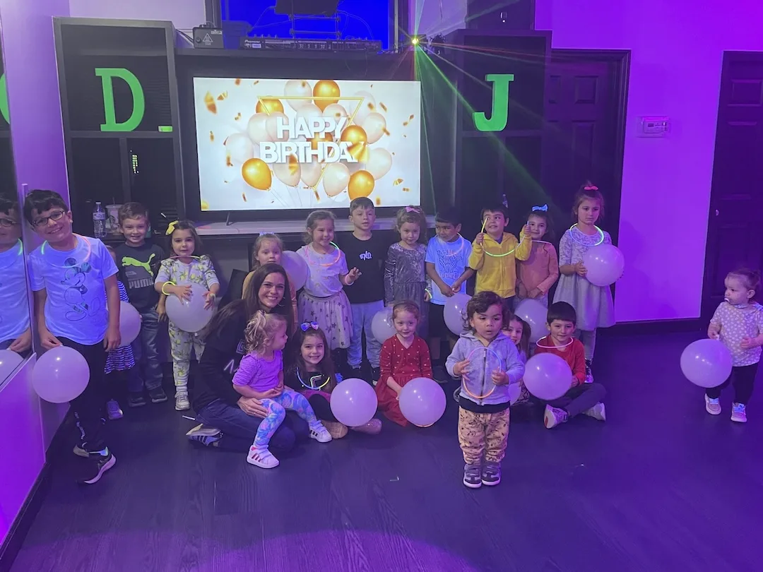 A DJ Got Me Fit birthday group under purple lights